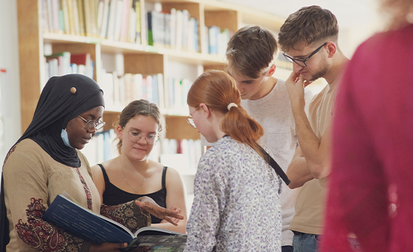 Jugendliche sind miteinander im Austausch und schauen dabei in ein Buch