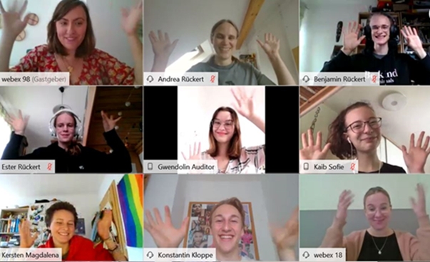 Screenshot von einer Gruppe, deren Portraitaufnahmen in Kachelansicht in einem Video-Chatprogram sichtbar sind und die alle die Hände ins Bild halten.