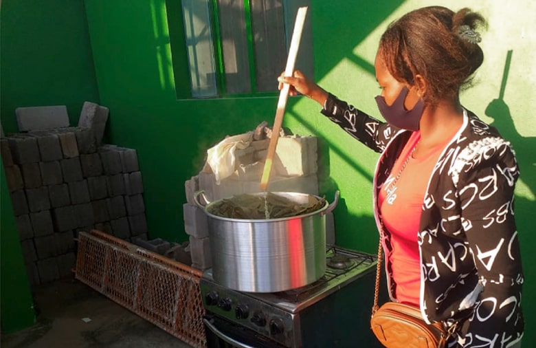Die mosambikanische Schülerin Cremilda Marcos rührt kochende Blätter in einem großen Topf um.