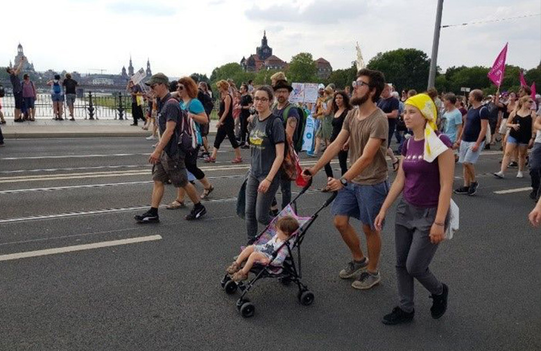 Auf dem Bild ist eine demonstrierende Gruppe zu sehen, die gerade über eine Brücke läuft.