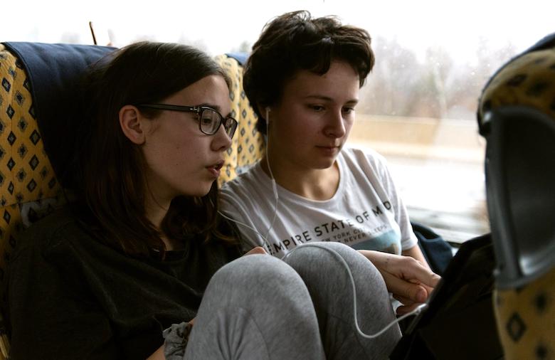 Die Schülerinnen Magdalena und Liv hören im Bus über Kopfhörer Musik.